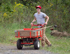 SD student pushing string trimmer in garden cart